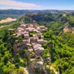 Vista panoramica del borgo italiano, con colline verdi e cielo azzurro, simbolo di bellezza e tranquillità.