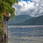 Panorama di un lago nascosto circondato da montagne, con acque tranquille e vegetazione lussureggiante.